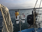 Hoisted, from the pushpit rail, with an old mainsheet block. Easy. Daily rations stored close by.