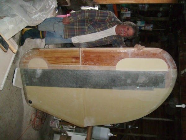 Bob Dixon, Master of composite construction, with board atop bathroom scale.  Weight at this stage about 90 pounds.  Note lightening holes filled with foam.  Board is now ready for final cloth and fairing.  Trailing edge is solid glass, about 2" wide. Note cutback of board at top (inverted).